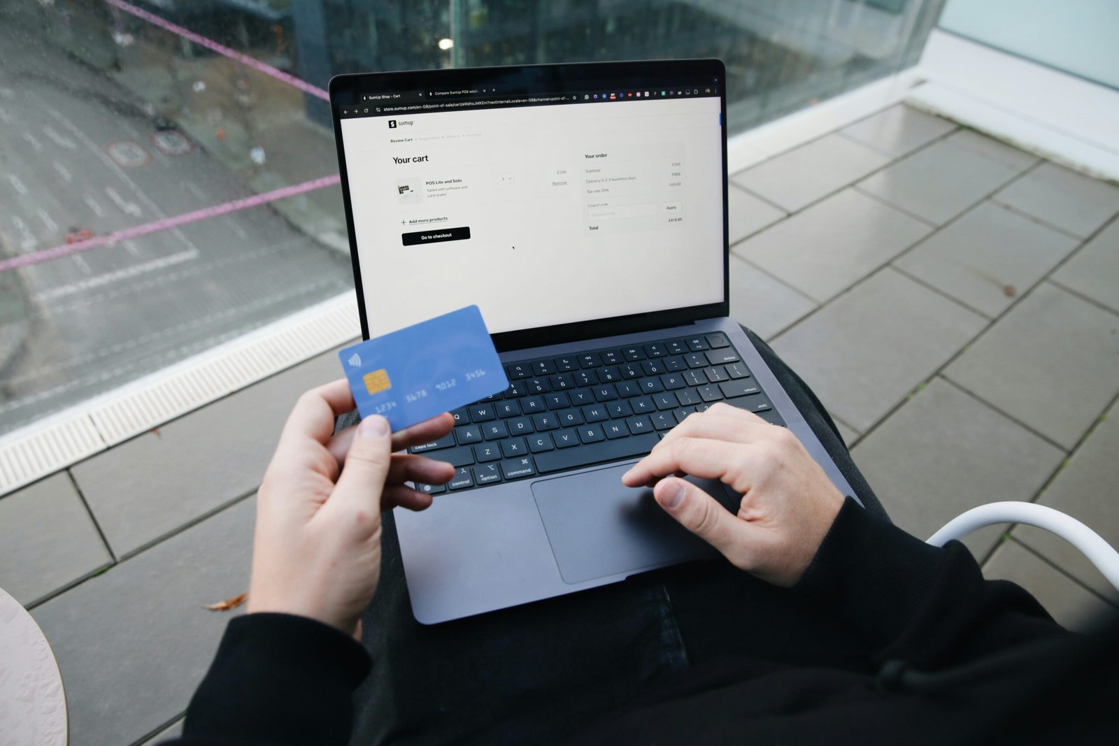 A person sitting in a chair with a laptop and a credit card