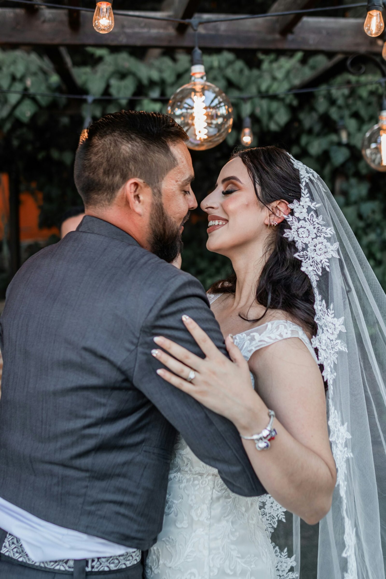a bride and groom embracing under a string of lights
