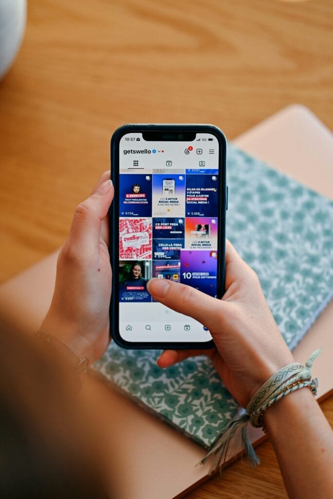 Manos sosteniendo el teléfono mostrando el feed de las redes sociales